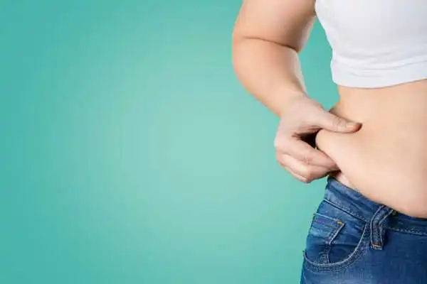 Image of woman pinching her love handles to show weight gain Ware